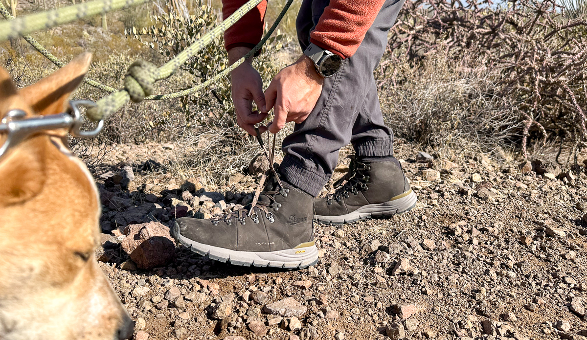 man tying hiking boots on trail