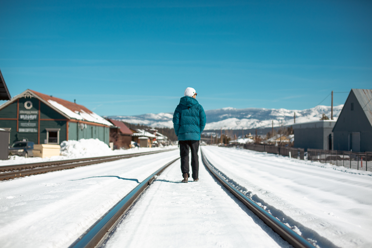 man walking on winter train tracks