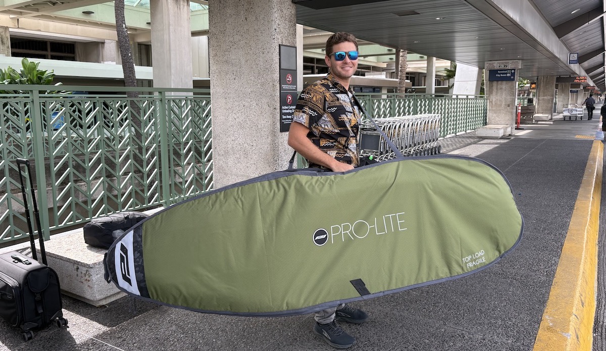 a man holding a surfboard bag at the airport