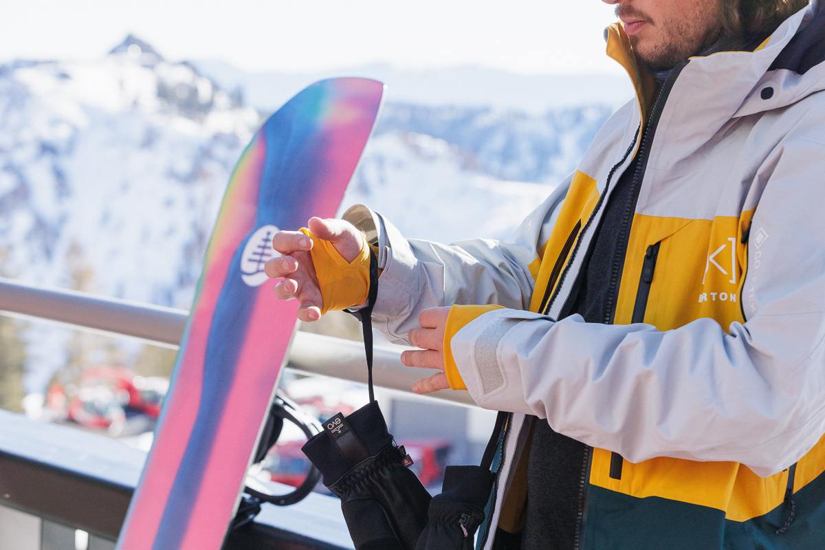 man adjusting snowboard jacket on mountain