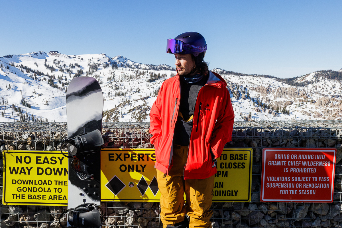 man standing at ski resort next to signs