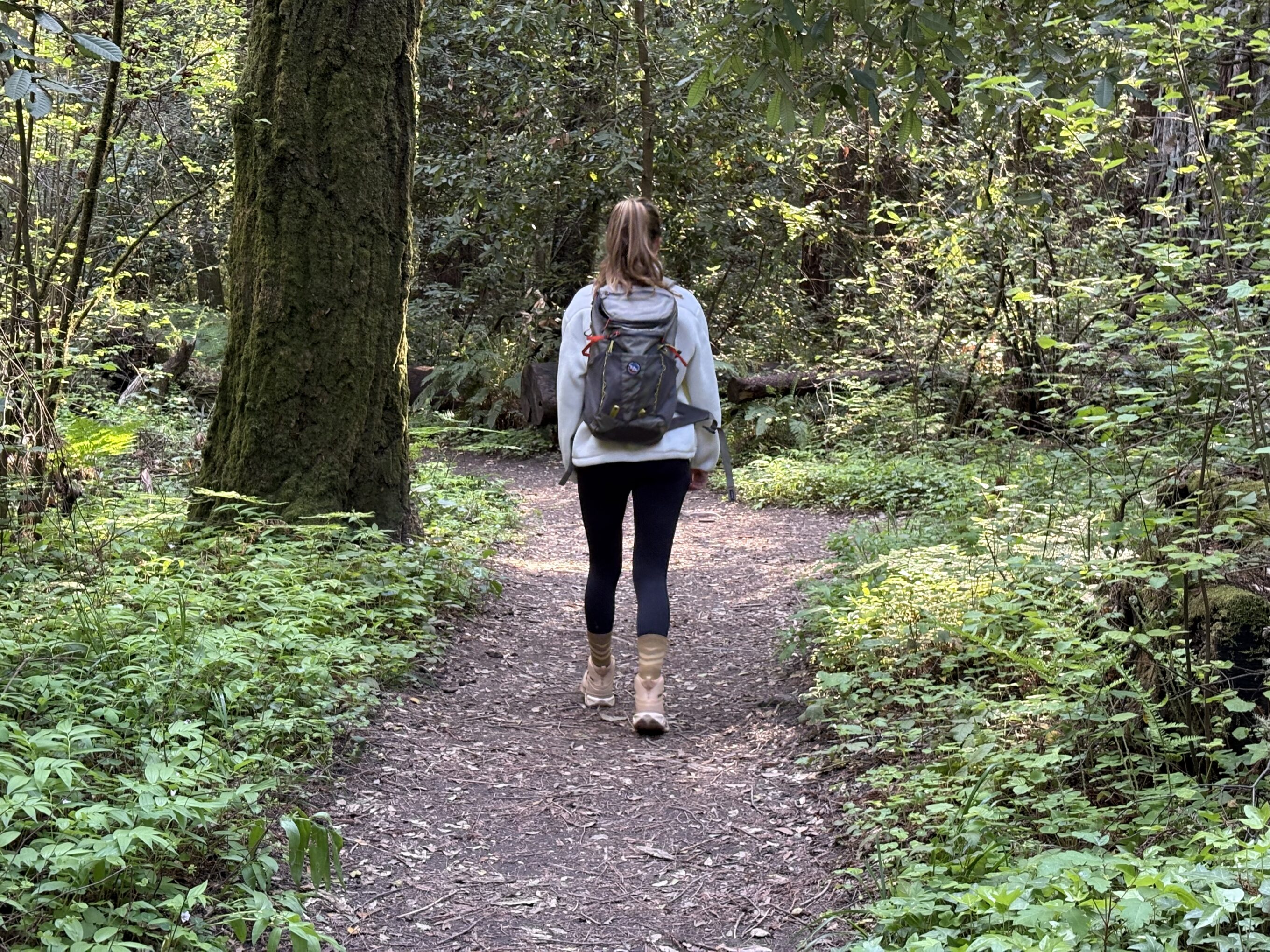 a woman walking in the forest wearing hiking boots