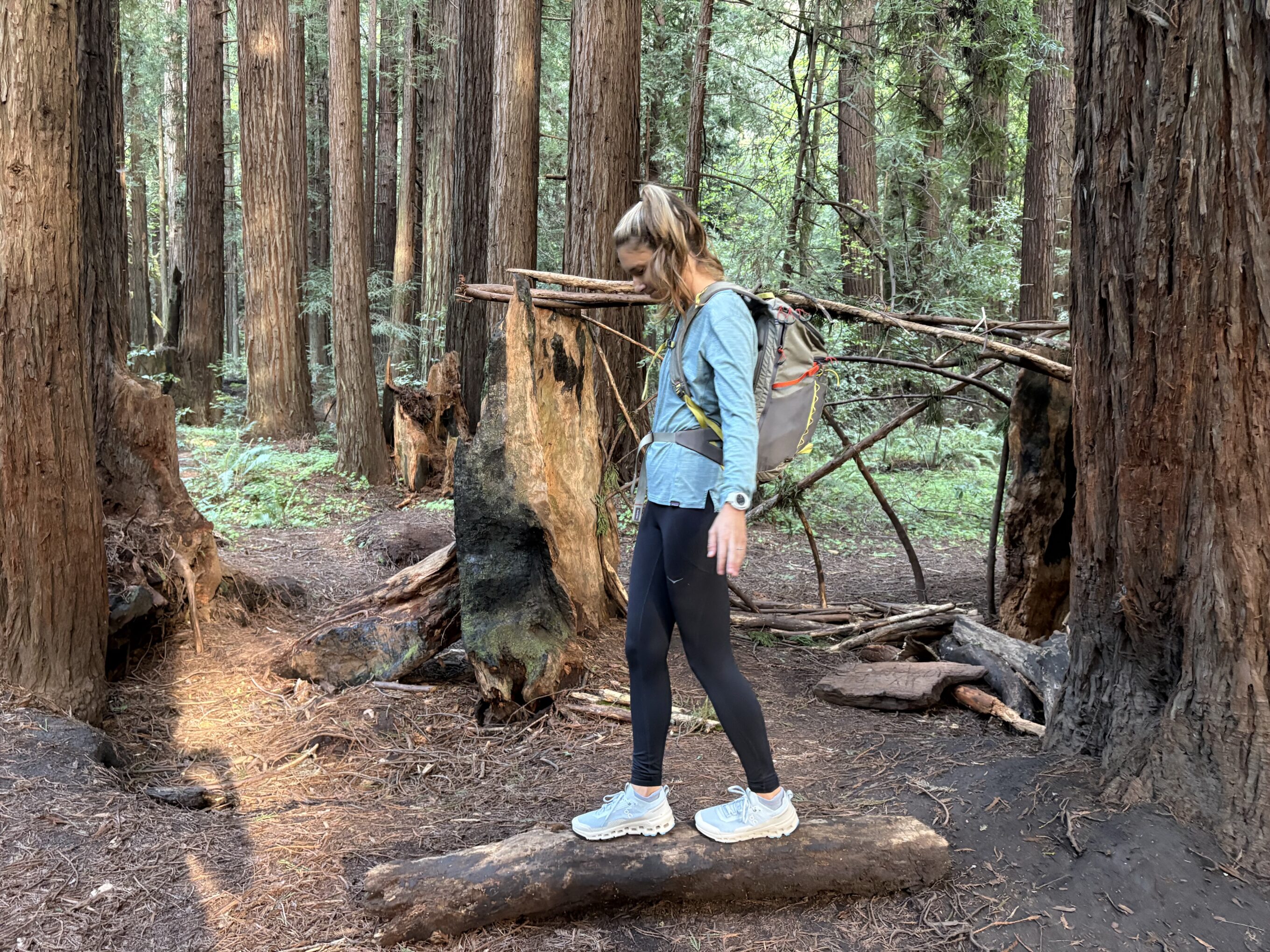 a woman walking on a log in the forest