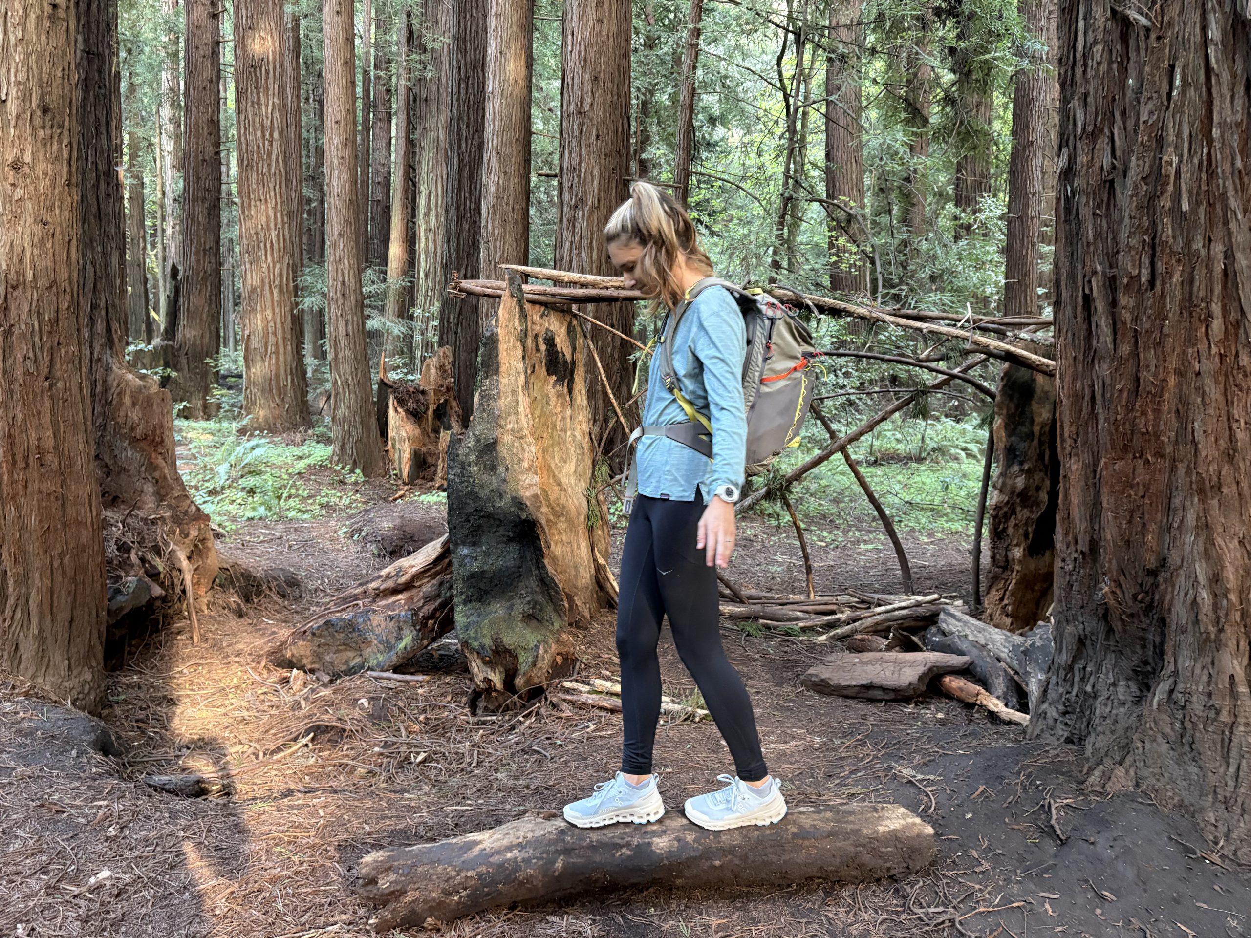 a woman walking on a log in the forest