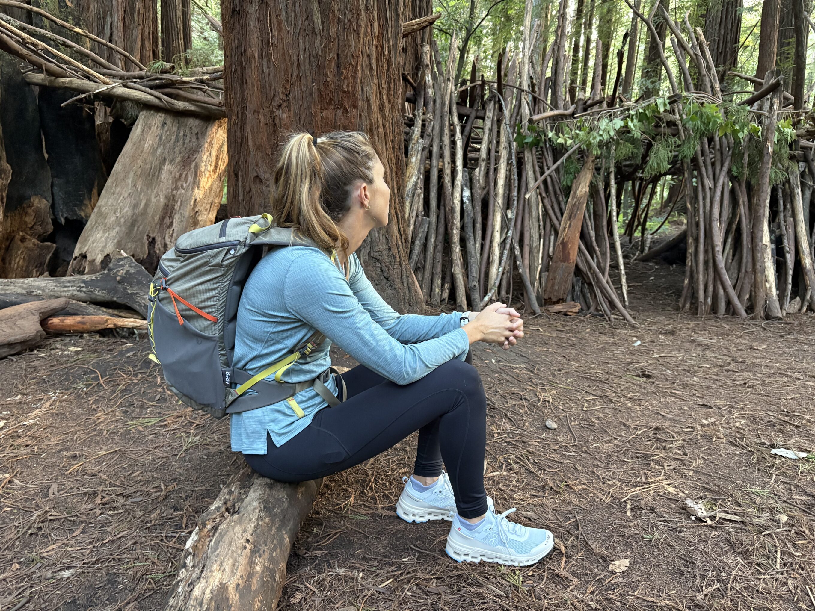 a woman sitting on a log in the forest
