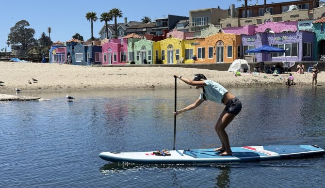 a woman paddling a red paddle co sport plus board