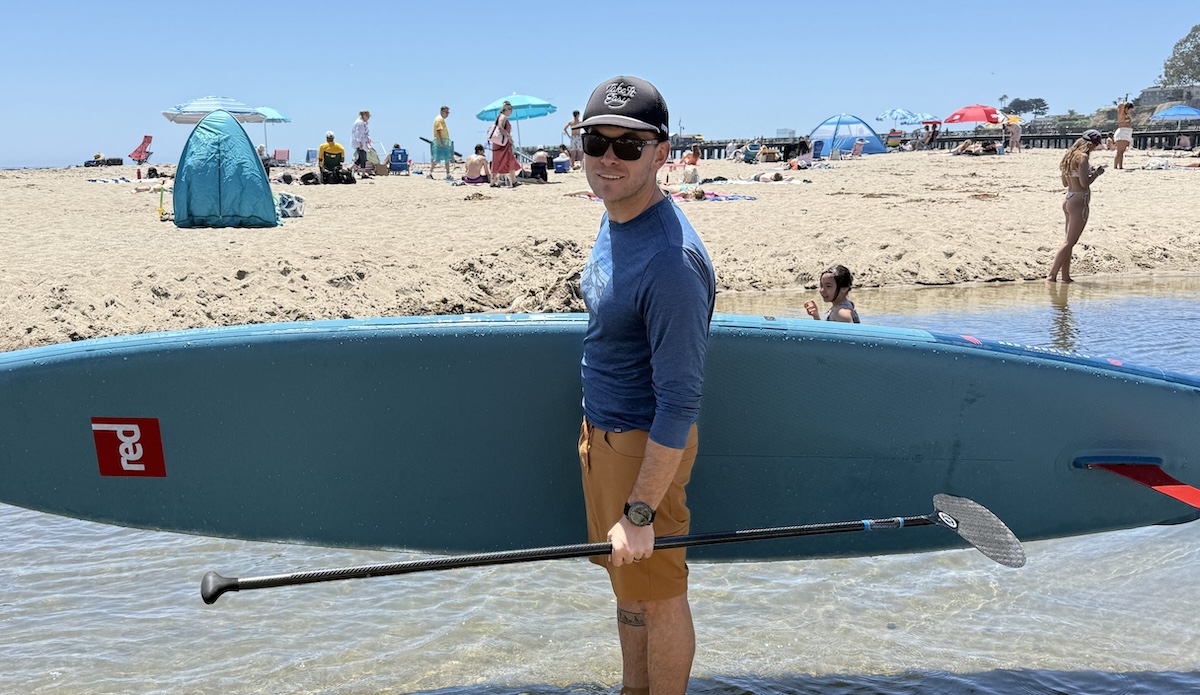 a man carrying a paddle board at the beach