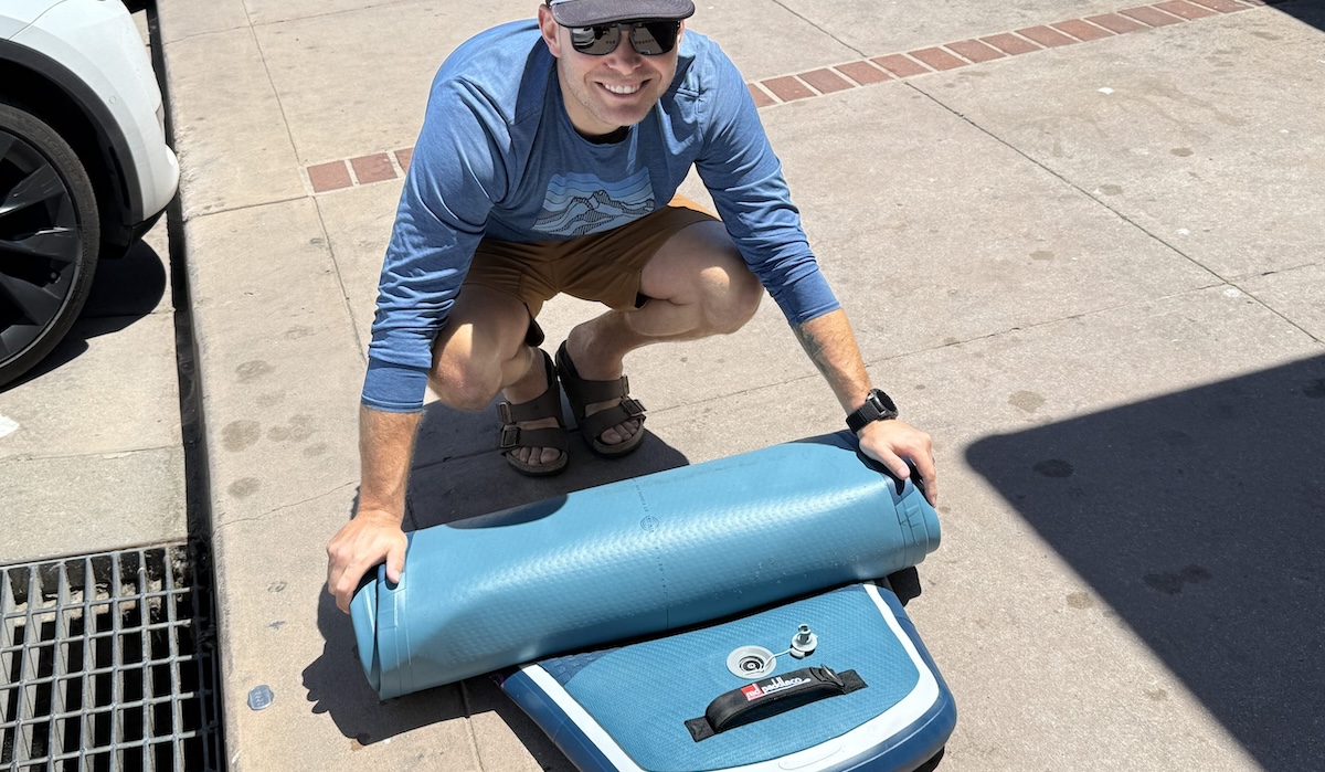 a man rolling up a paddle board
