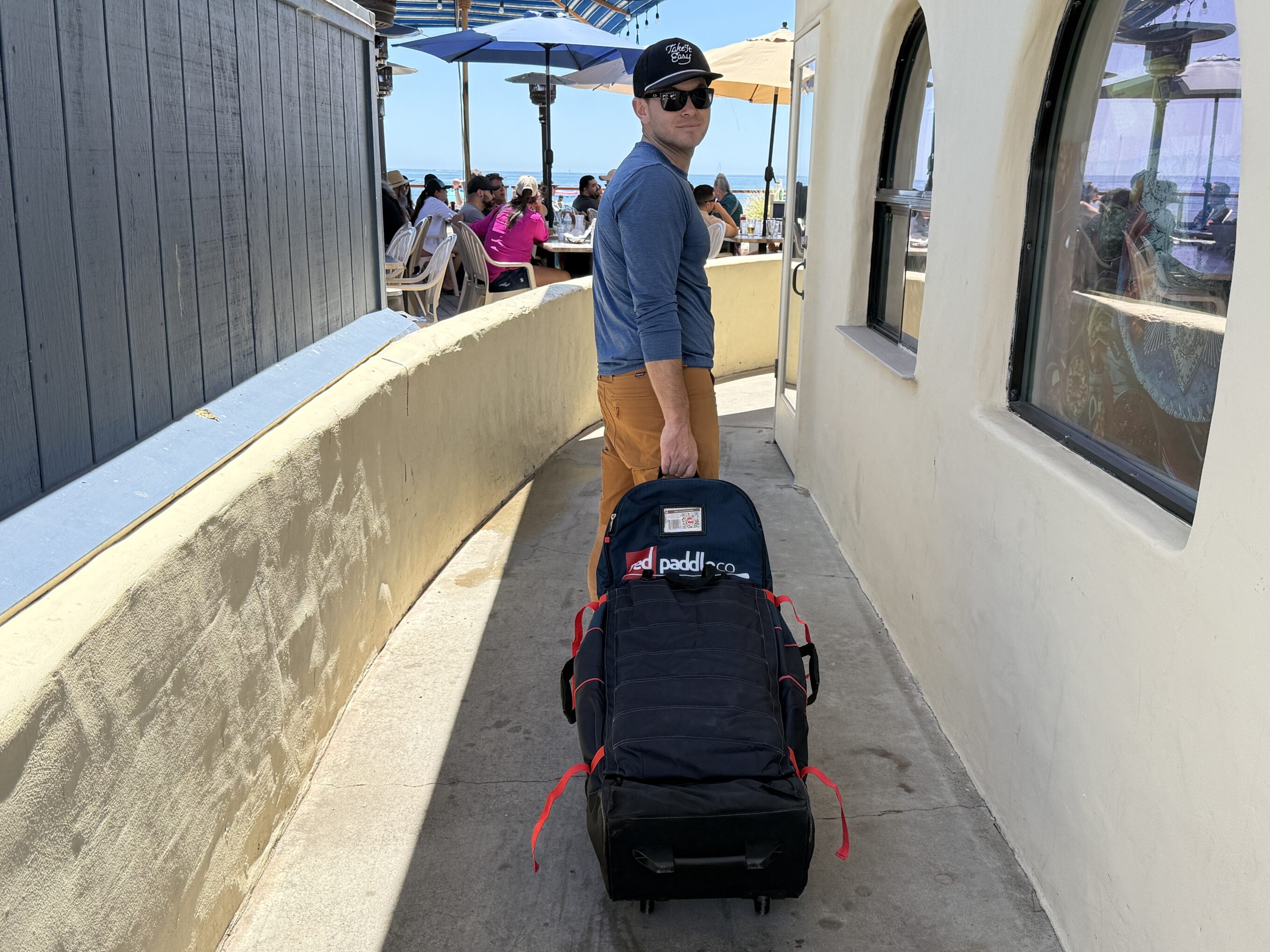 a man wheeling a paddle board bag