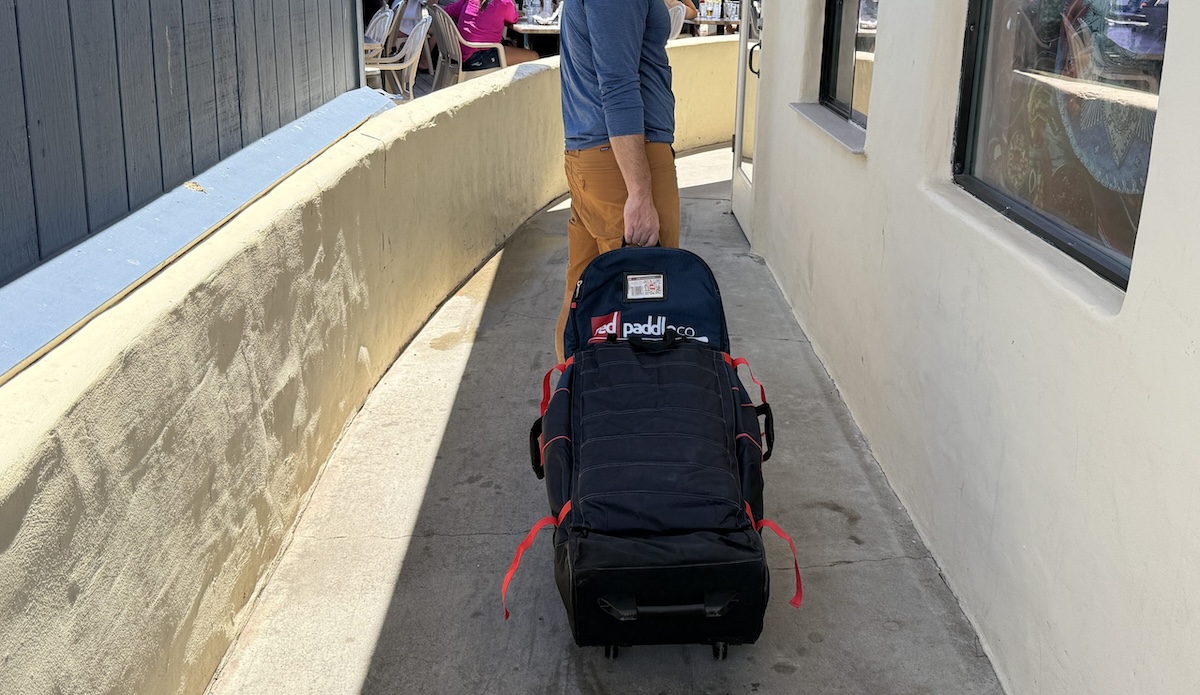a man wheeling a paddle board bag