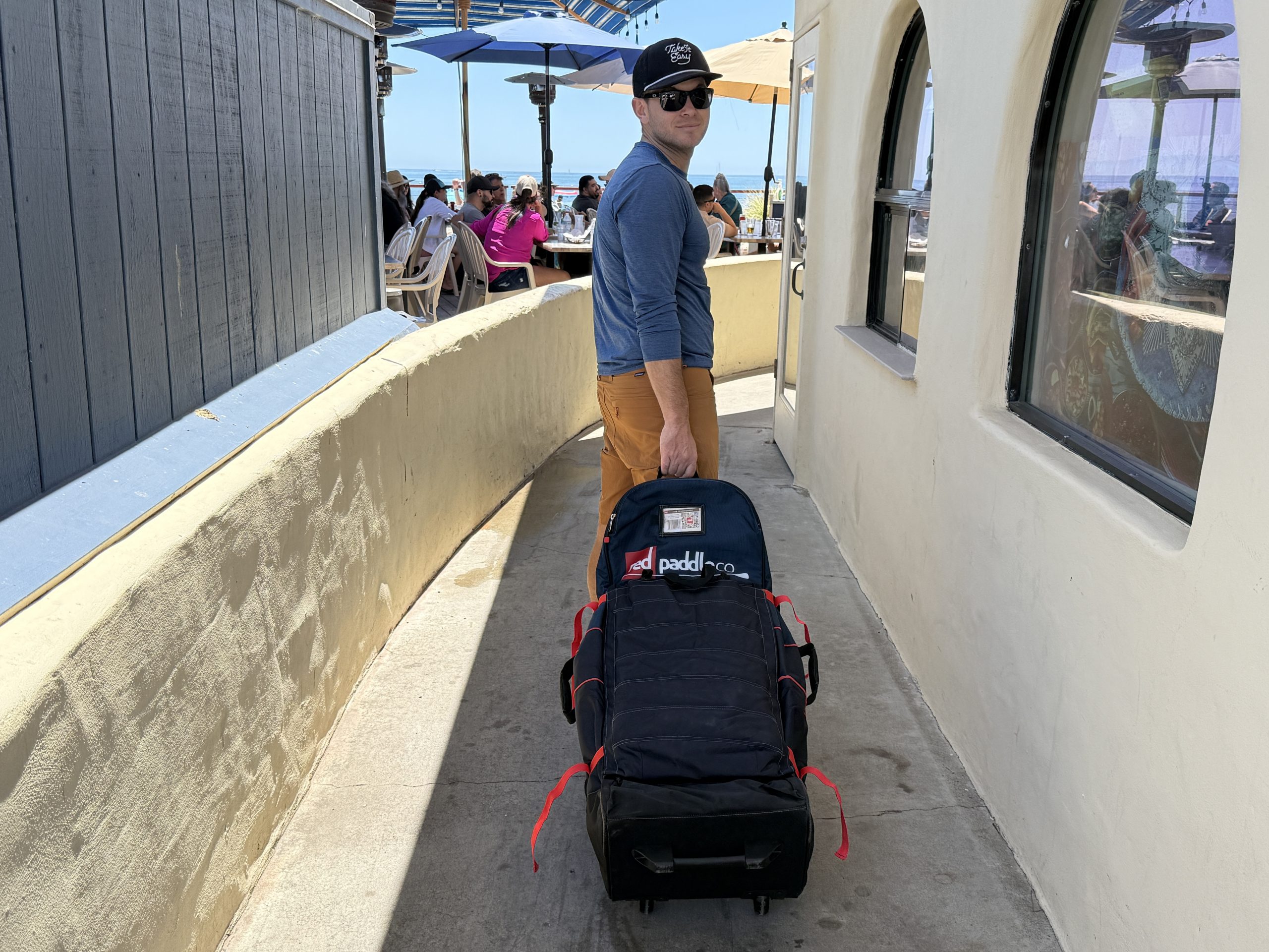 a man wheeling a paddle board bag