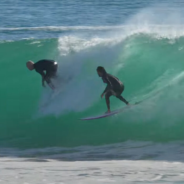 Superbank surfer dropping in on another surfer