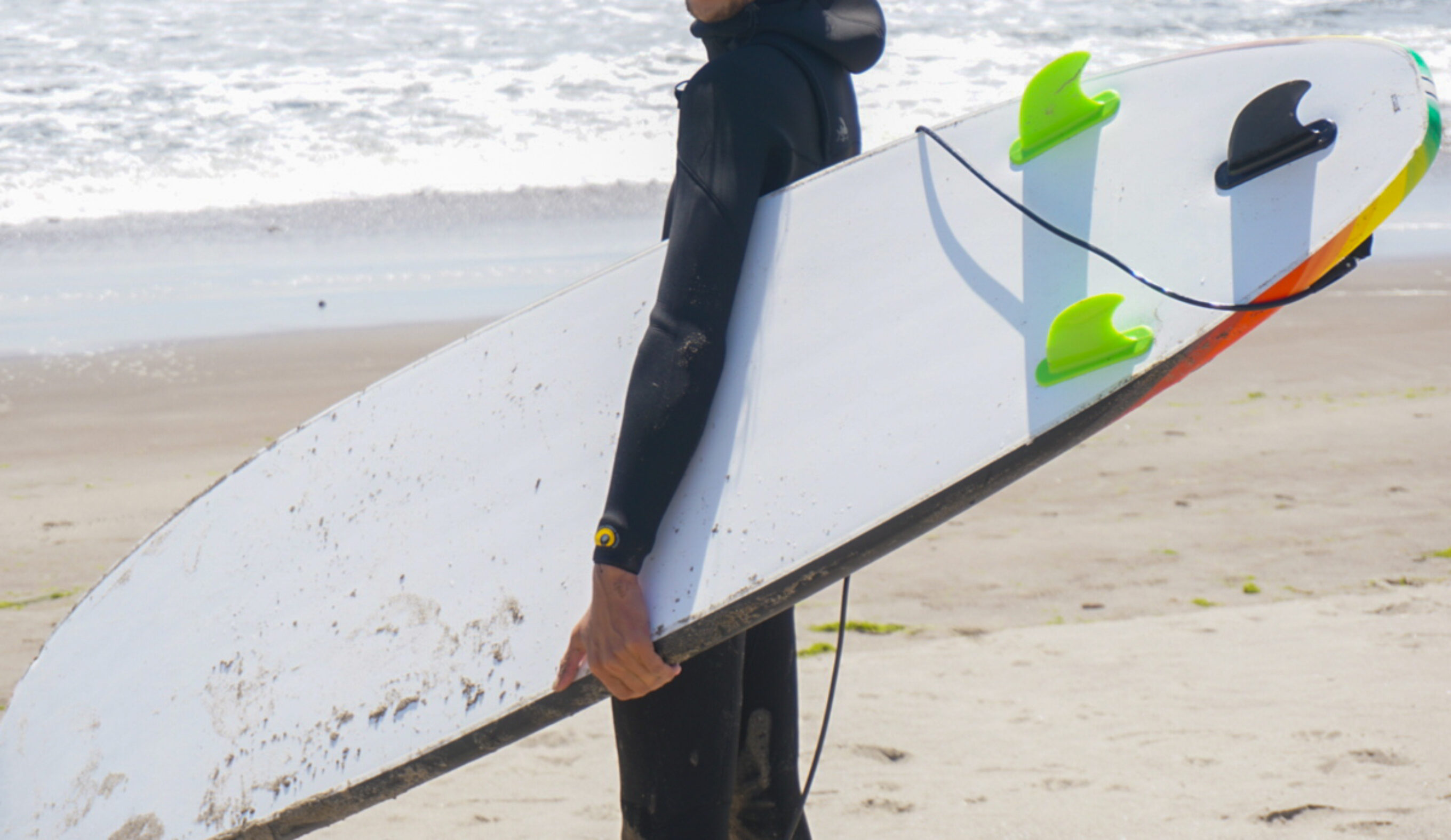 Will Sileo holding a wavestorm on the beach, showing the underside, and fins