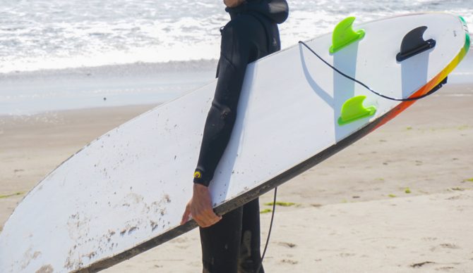 Will Sileo holding a wavestorm on the beach, showing the underside, and fins