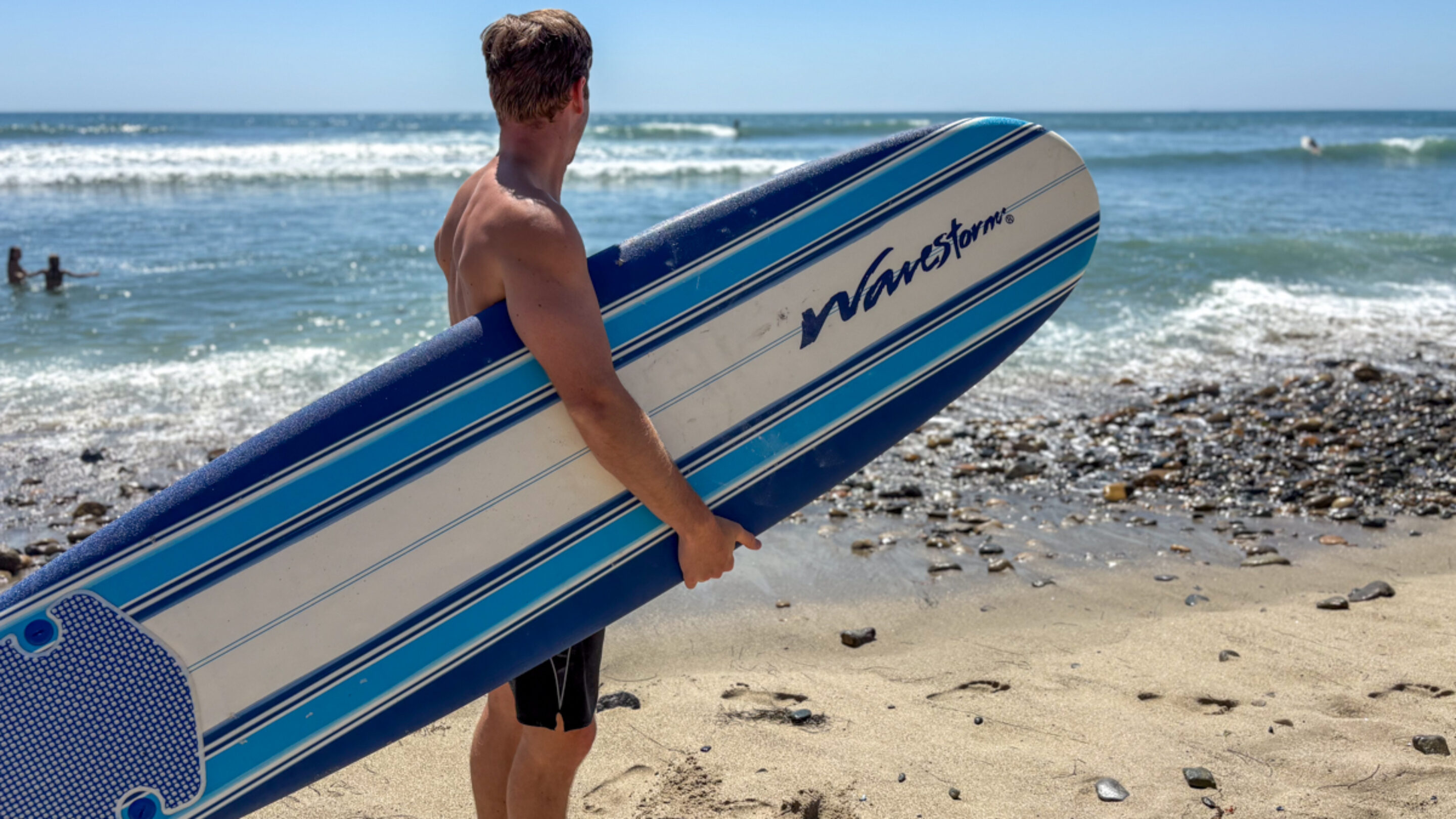 Dylan holds a wavestorm on the beach and looks out at the waves