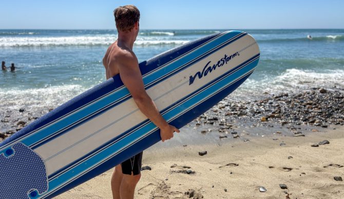 Dylan holds a wavestorm on the beach and looks out at the waves