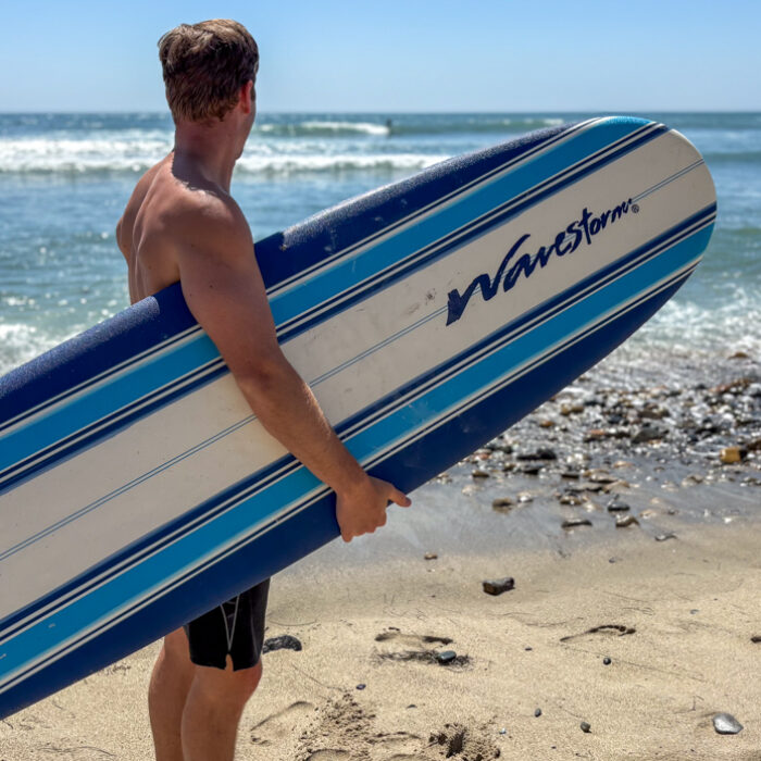 Dylan holds a wavestorm on the beach and looks out at the waves