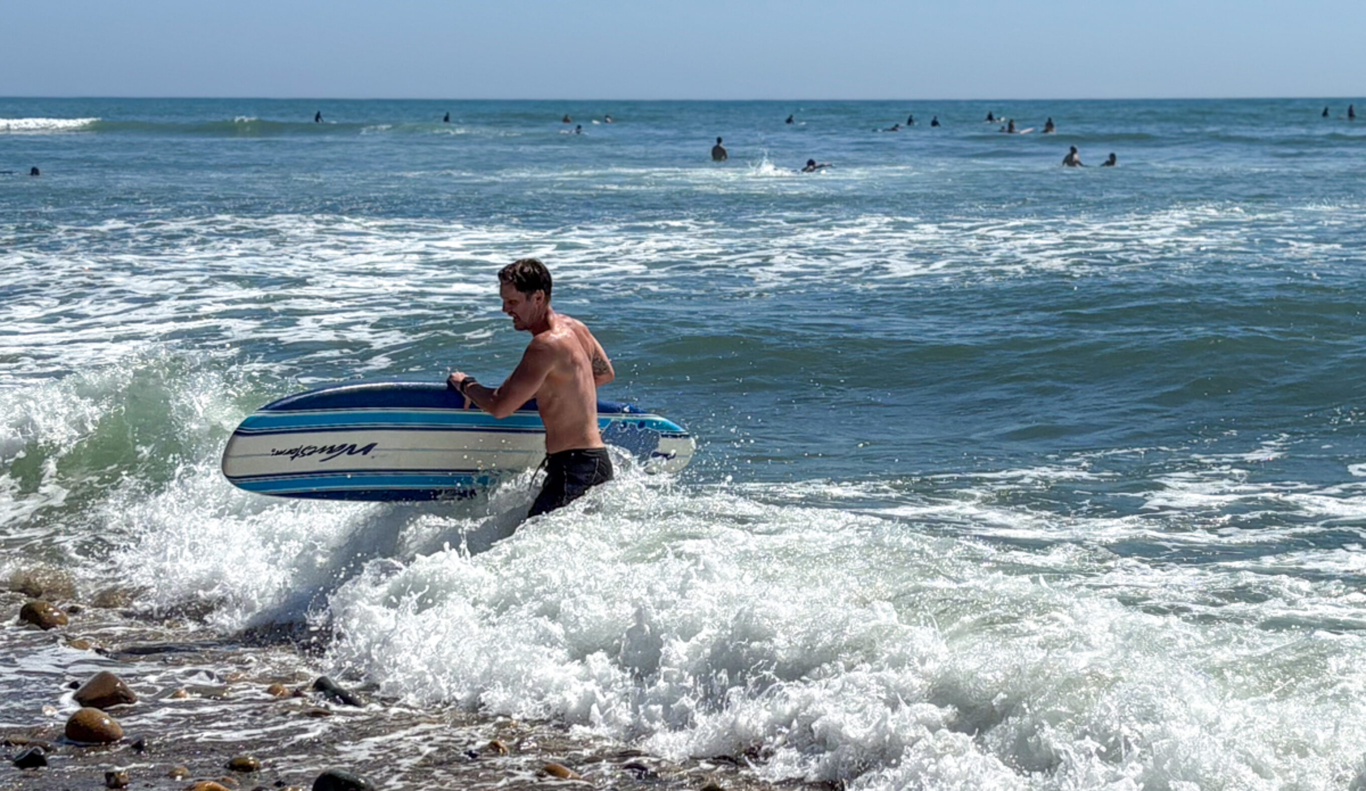 Dylan exits the water with a wavestorm after surfing