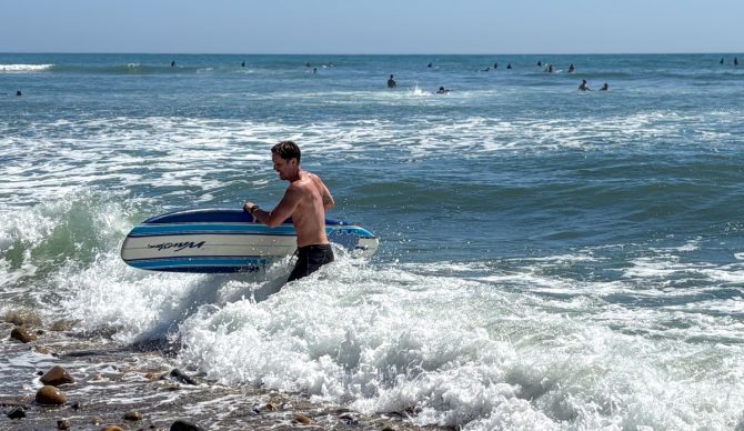 Dylan exits the water with a wavestorm after surfing
