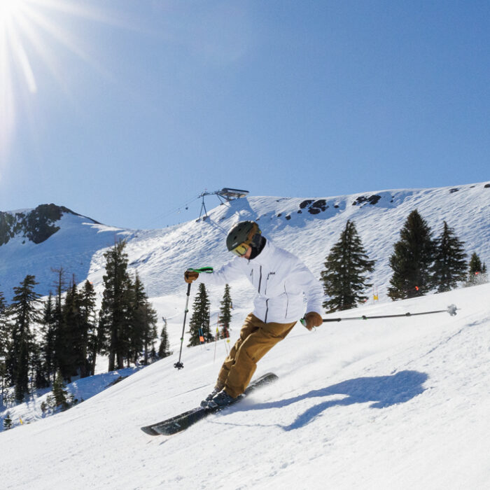 skiing in the HH Alpha 4.0 ski jacket and flylow baker bibs