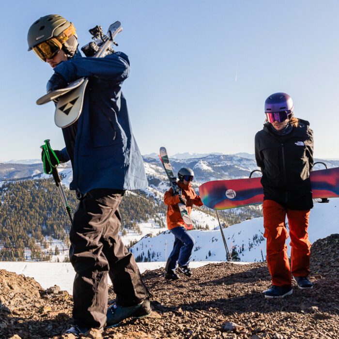 three men hiking up mountain with snowboard and ski gear
