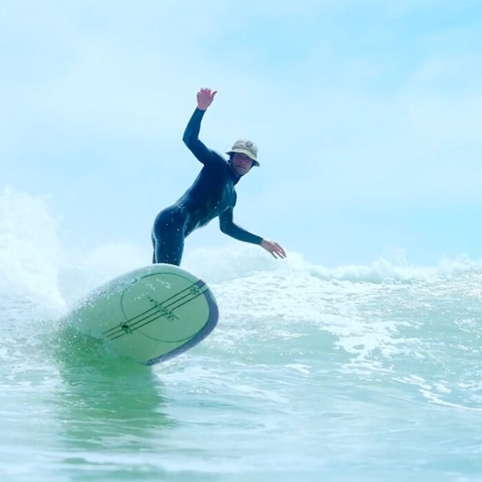 A man surfing with a surf helmet/bucket hat