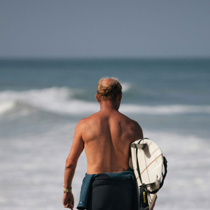 surfer with surfboard and sunscreens on his shoulders