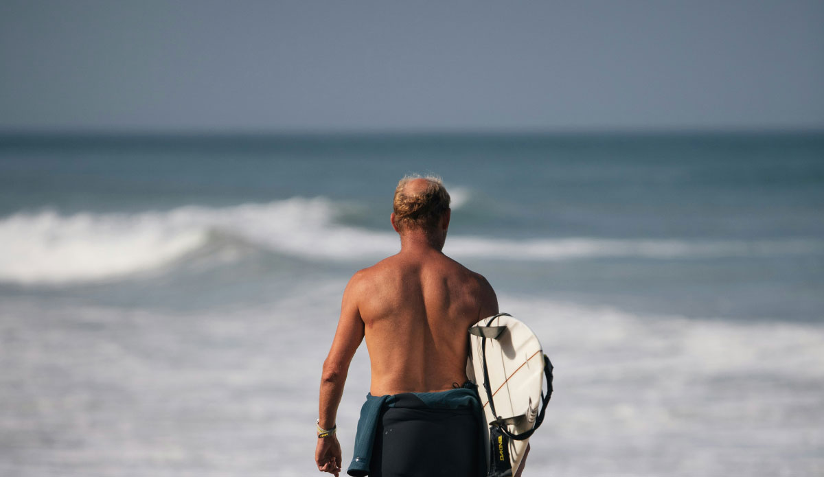 surfer with surfboard and sunscreen on his shoulders 