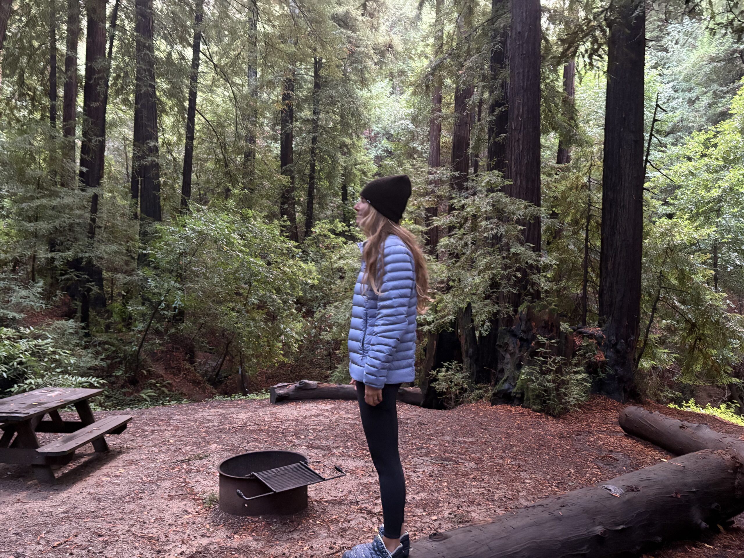 a woman in the forest wearing a puffer jacket 