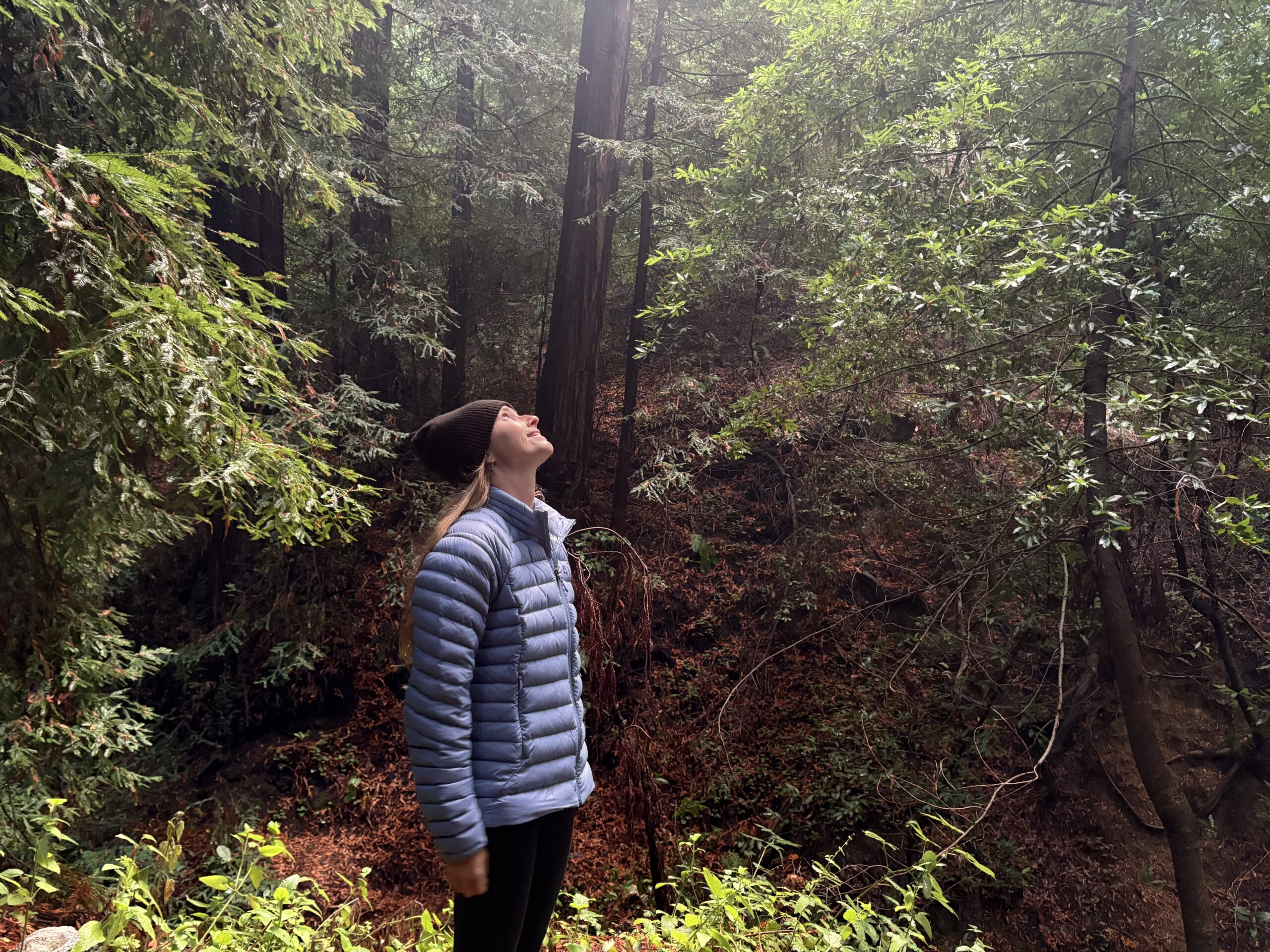 a woman in the forest wearing a puffer jacket 