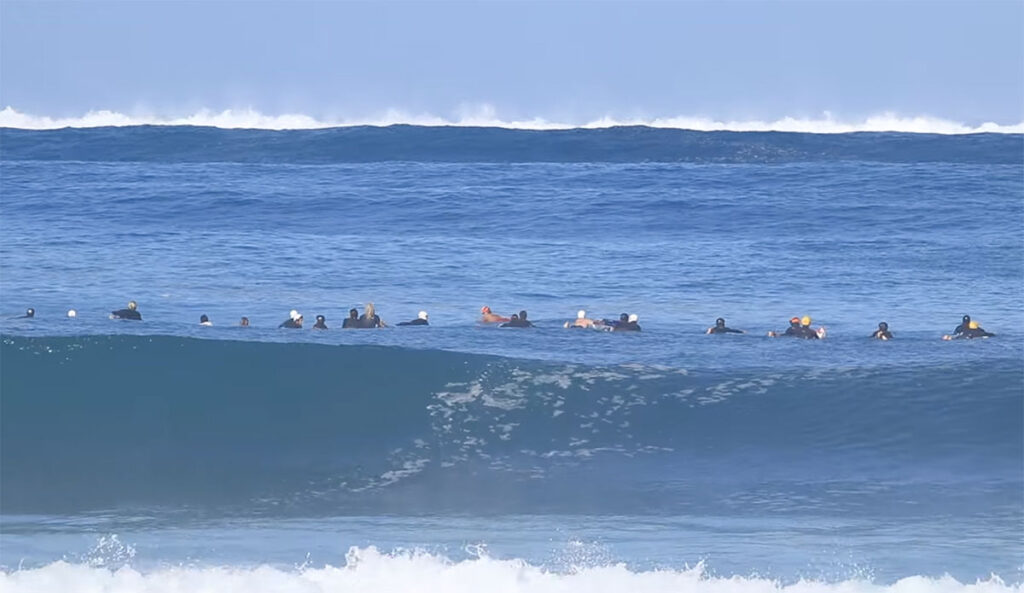 Pipeline surfers paddling towards incoming waves