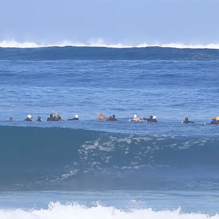Pipeline surfers paddling towards incoming waves