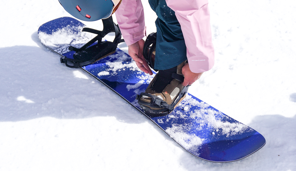 man strapping in snowboard bindings