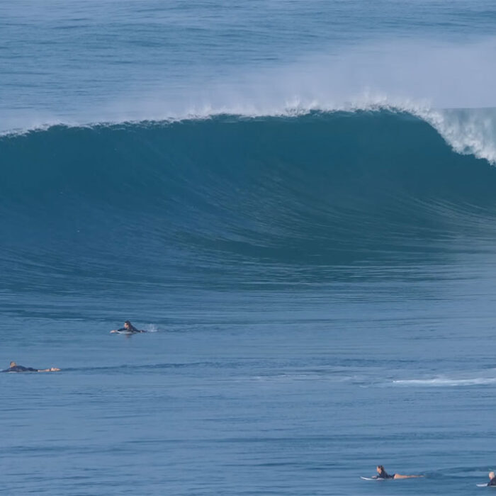 Indonesia wave breaking with surfers paddling towards it