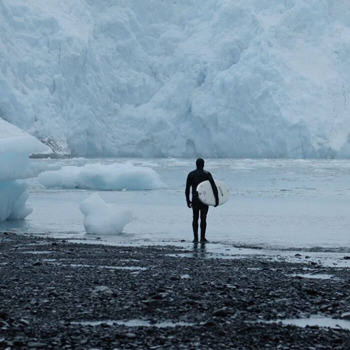 Ben Gravy standing with a surfboard in Alaska