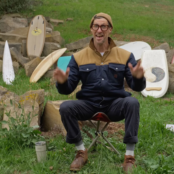 Donald Brink sitting in front of surfboards he made