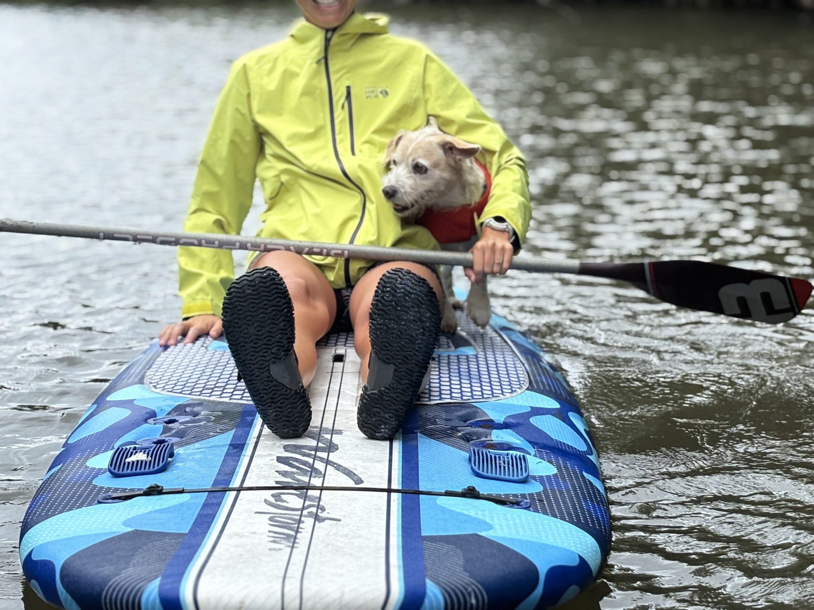 a woman on a paddle board with a dog