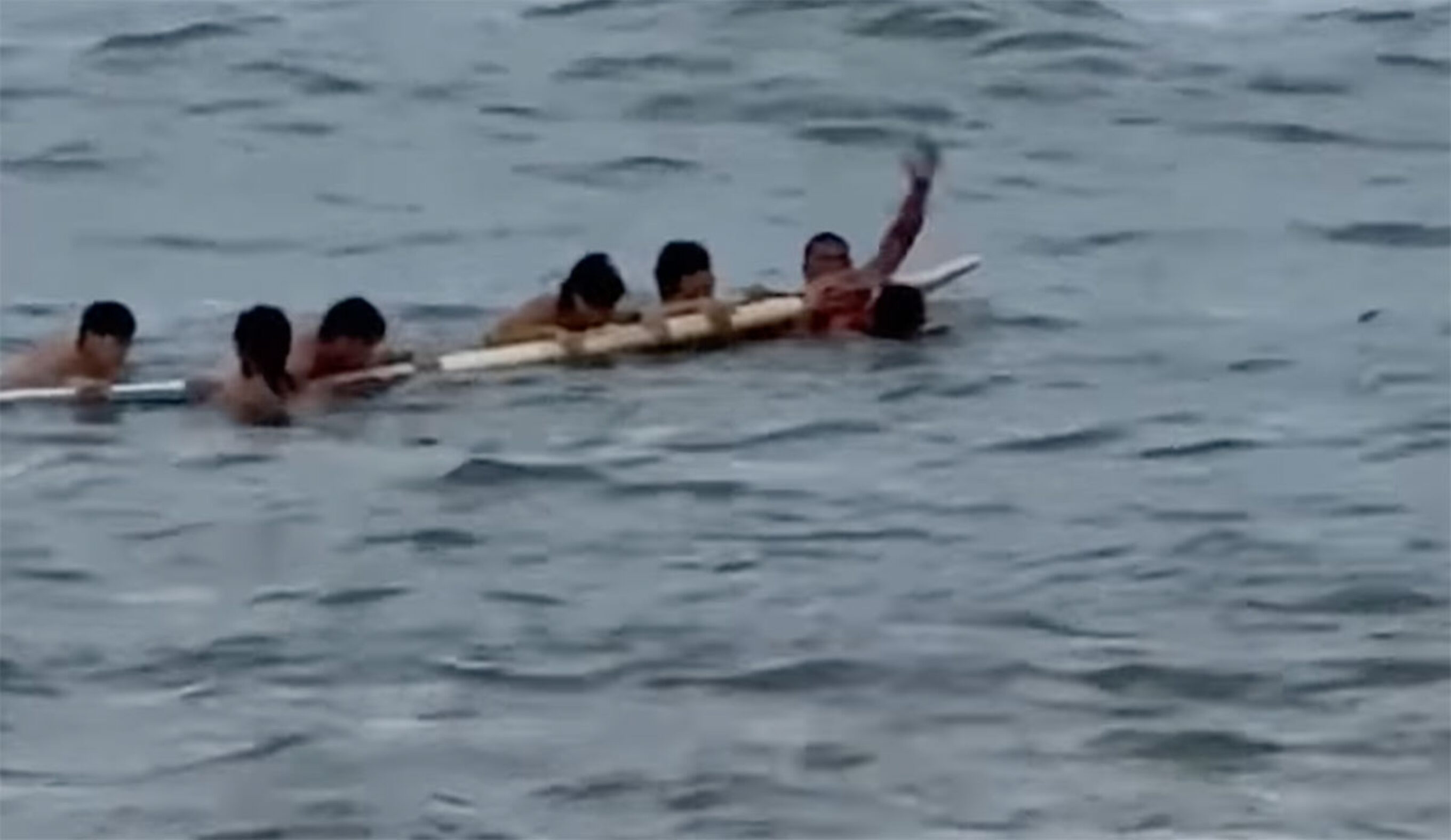 Oahu lifeguard with swimmers on his rescue board