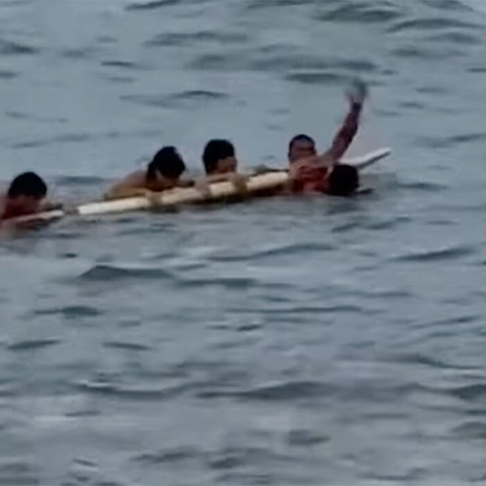Oahu lifeguard with swimmers on his rescue board