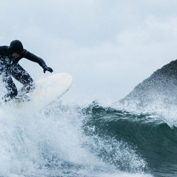 Surfer riding a wave in a Finisterre wetsuit